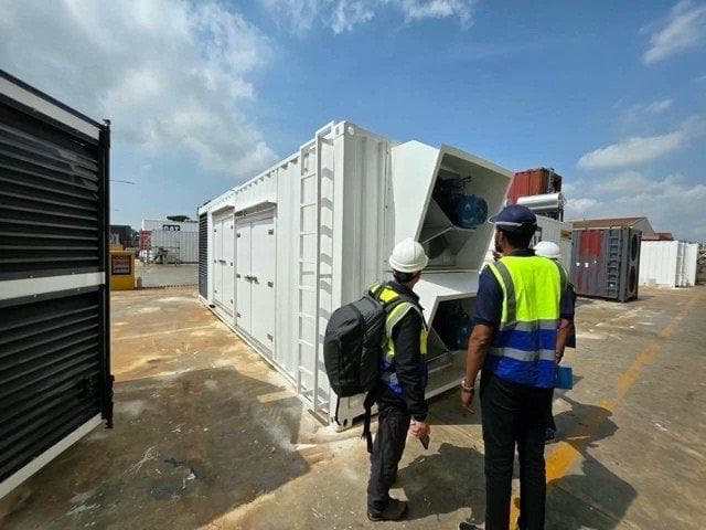 Partner Nigeria hosting site — technicians inspecting containerised generation